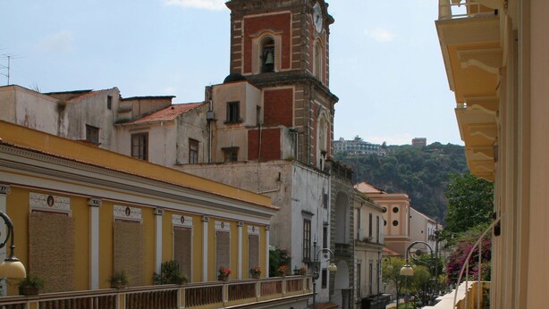 A street view with buildings, a clock tower, and a clear sky. - Corso Italia Suites (Sorrento)