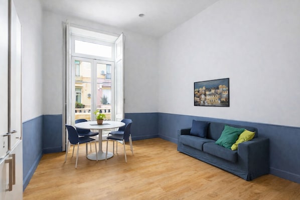 Una habitación con una mesa redonda, sillas, un sofá azul y un cuadro en la pared.