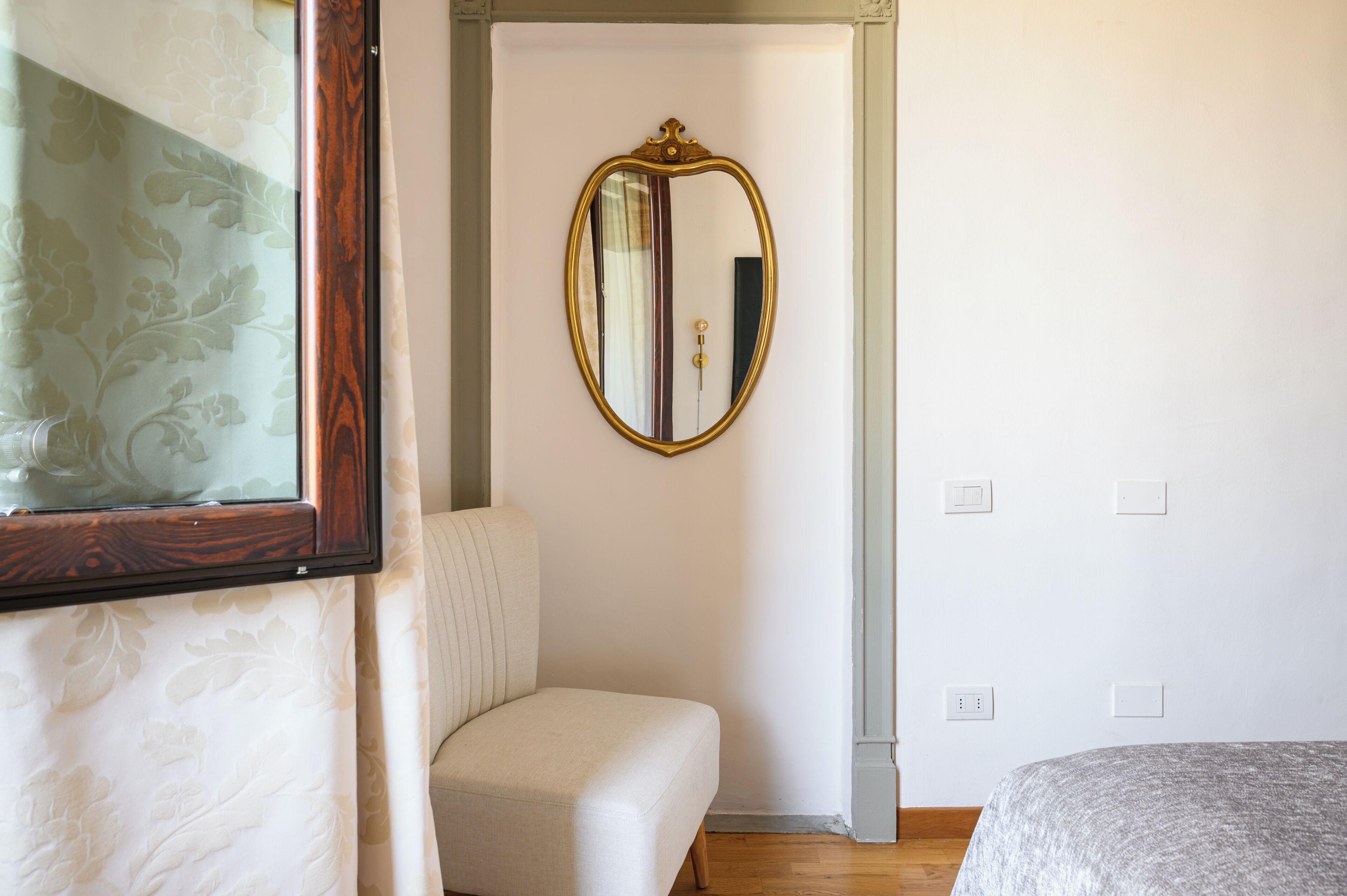 A bedroom with a bed, a chair, a mirror, and a door.