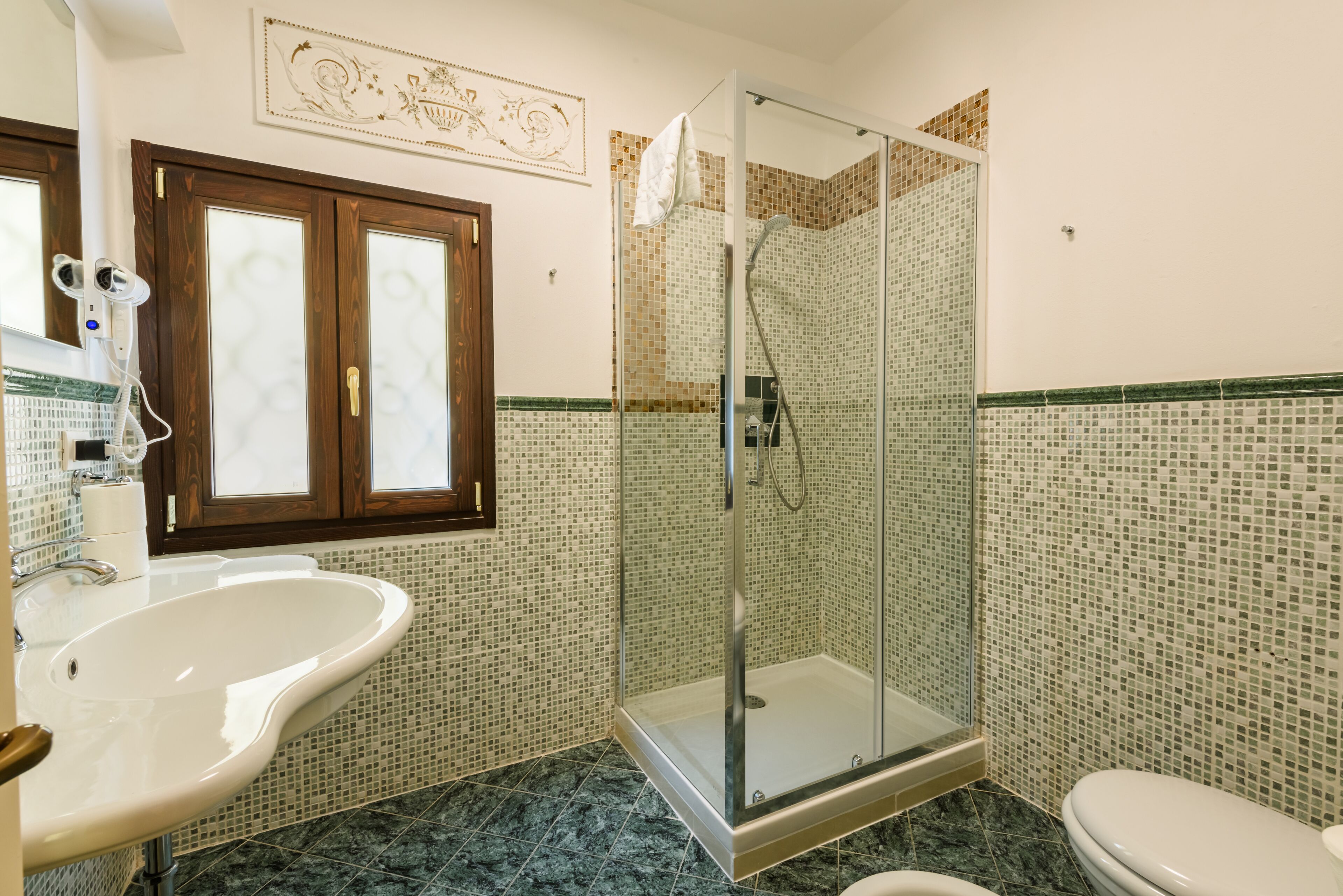 A bathroom with a glass-enclosed shower, a white sink, and a toilet.