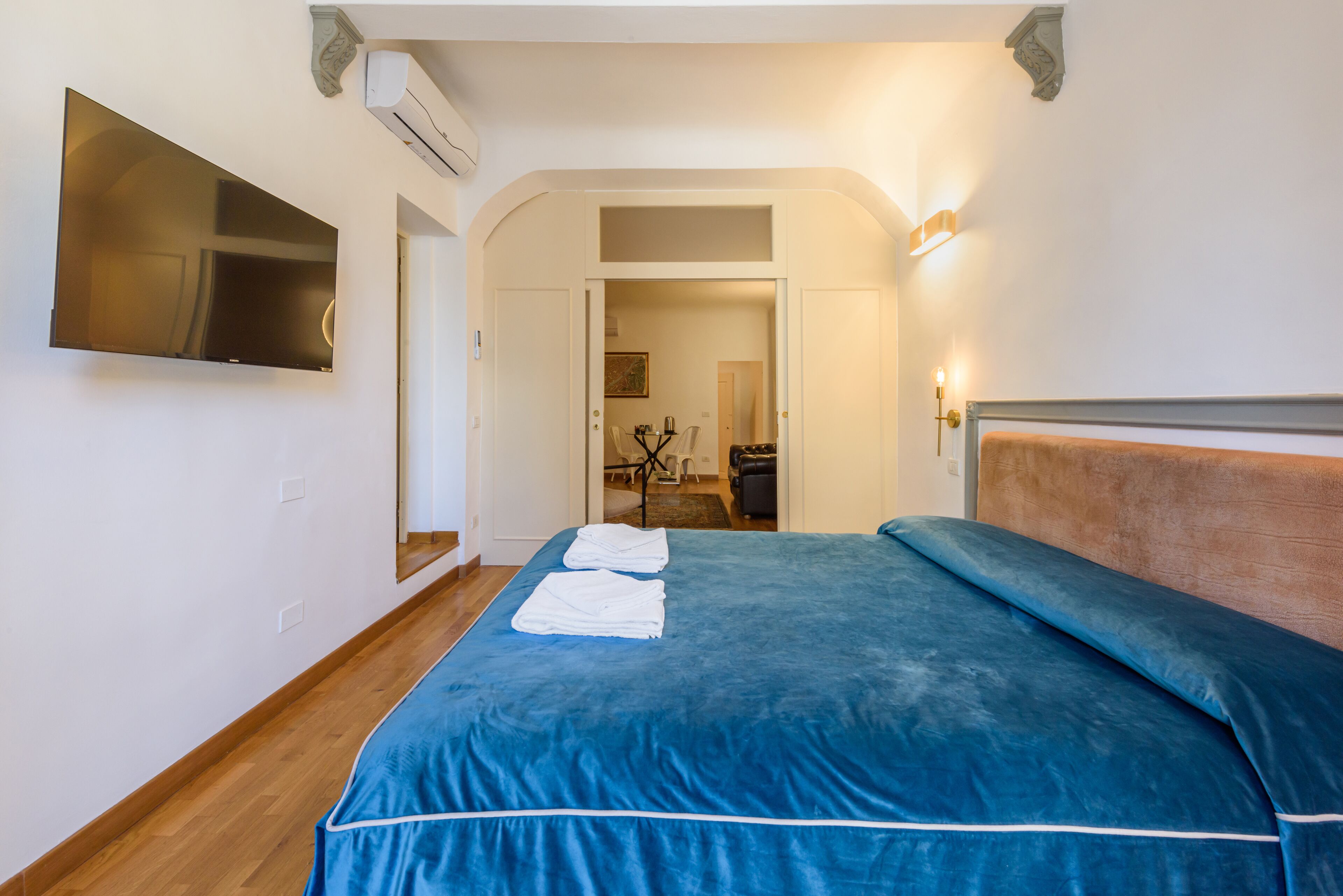 Une chambre dotée d’un grand lit, d’un téléviseur à écran plat fixé au mur et d’une porte donnant sur un coin repas.