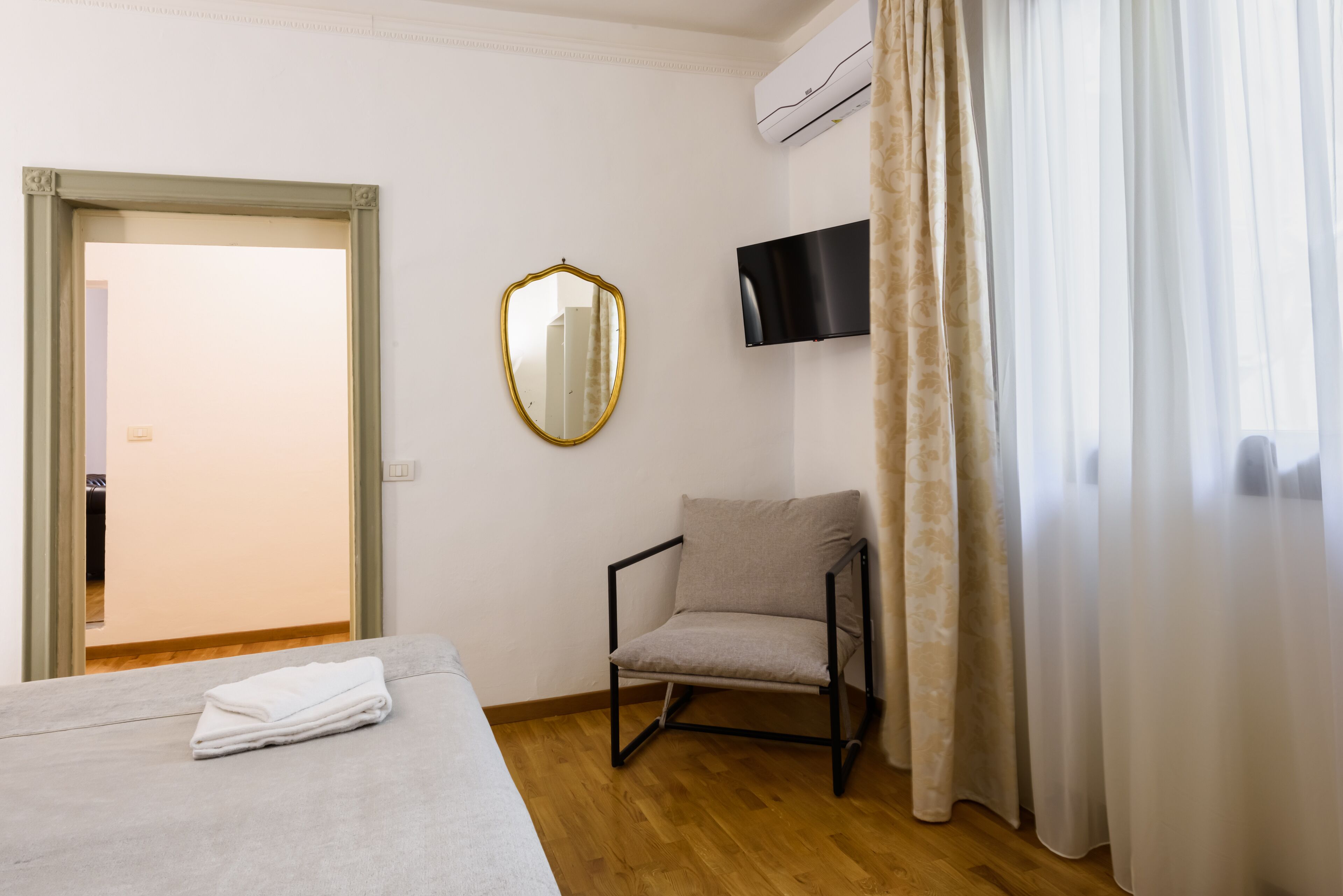A hotel room with a bed, a chair, a television, and a mirror.