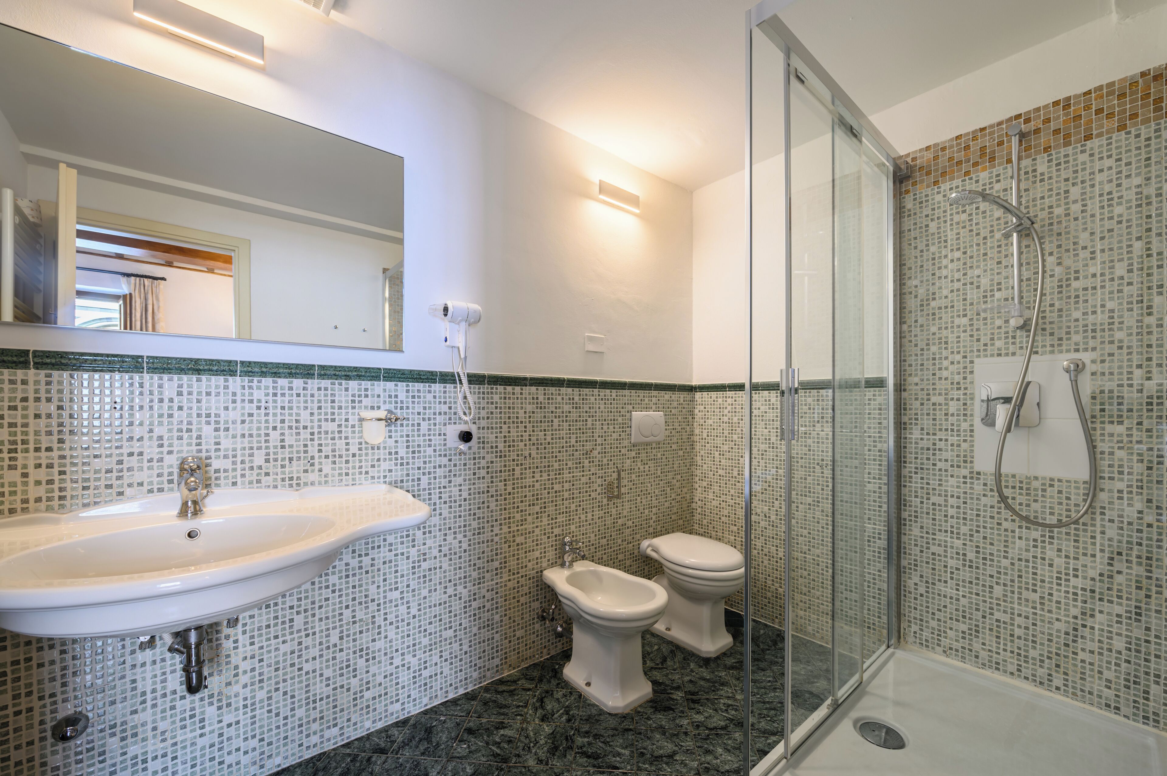 Ein Badezimmer mit einer Duschkabine, einem Waschbecken und zwei Toiletten.