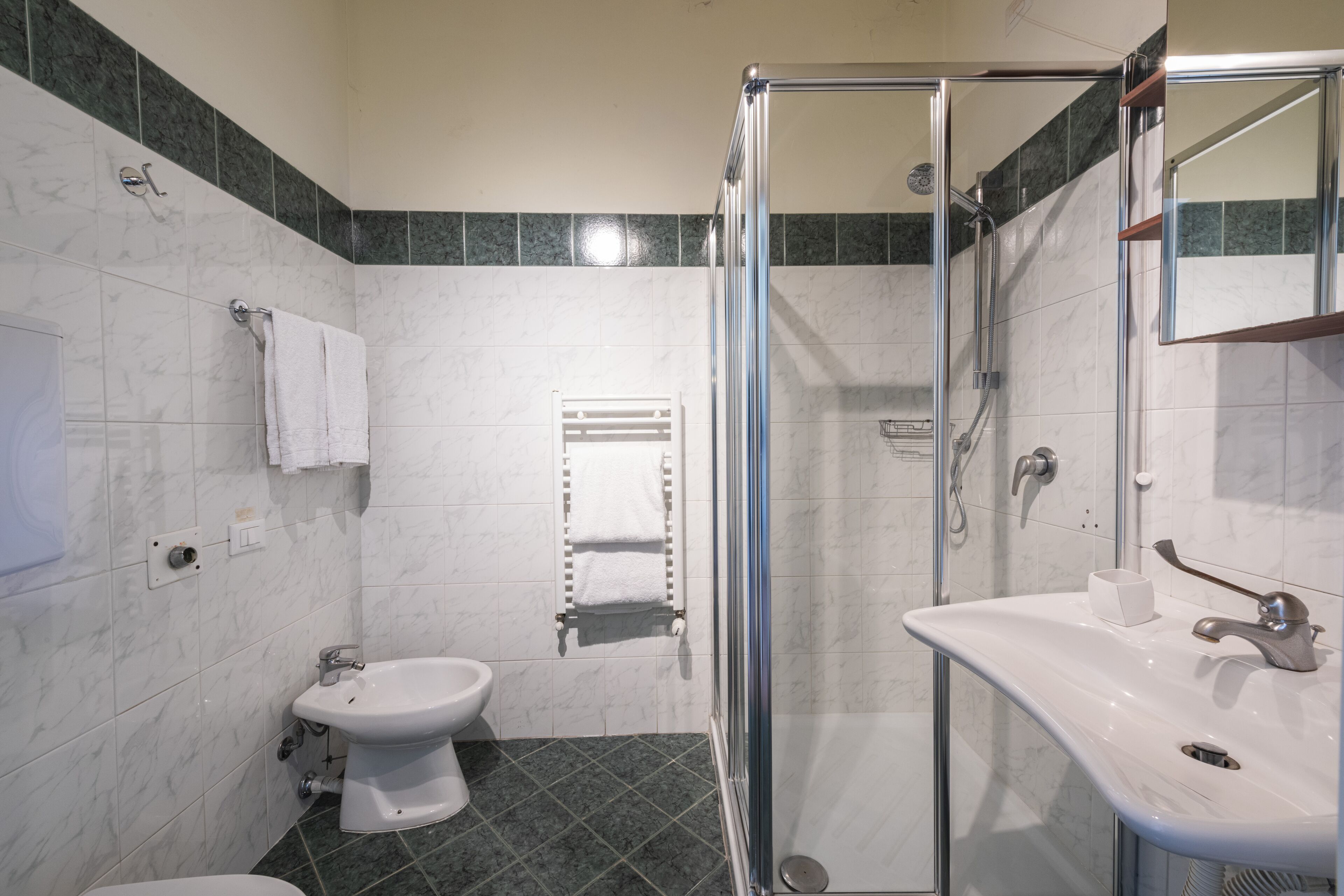 A modern bathroom with a glass-enclosed shower, a white sink, and a toilet.