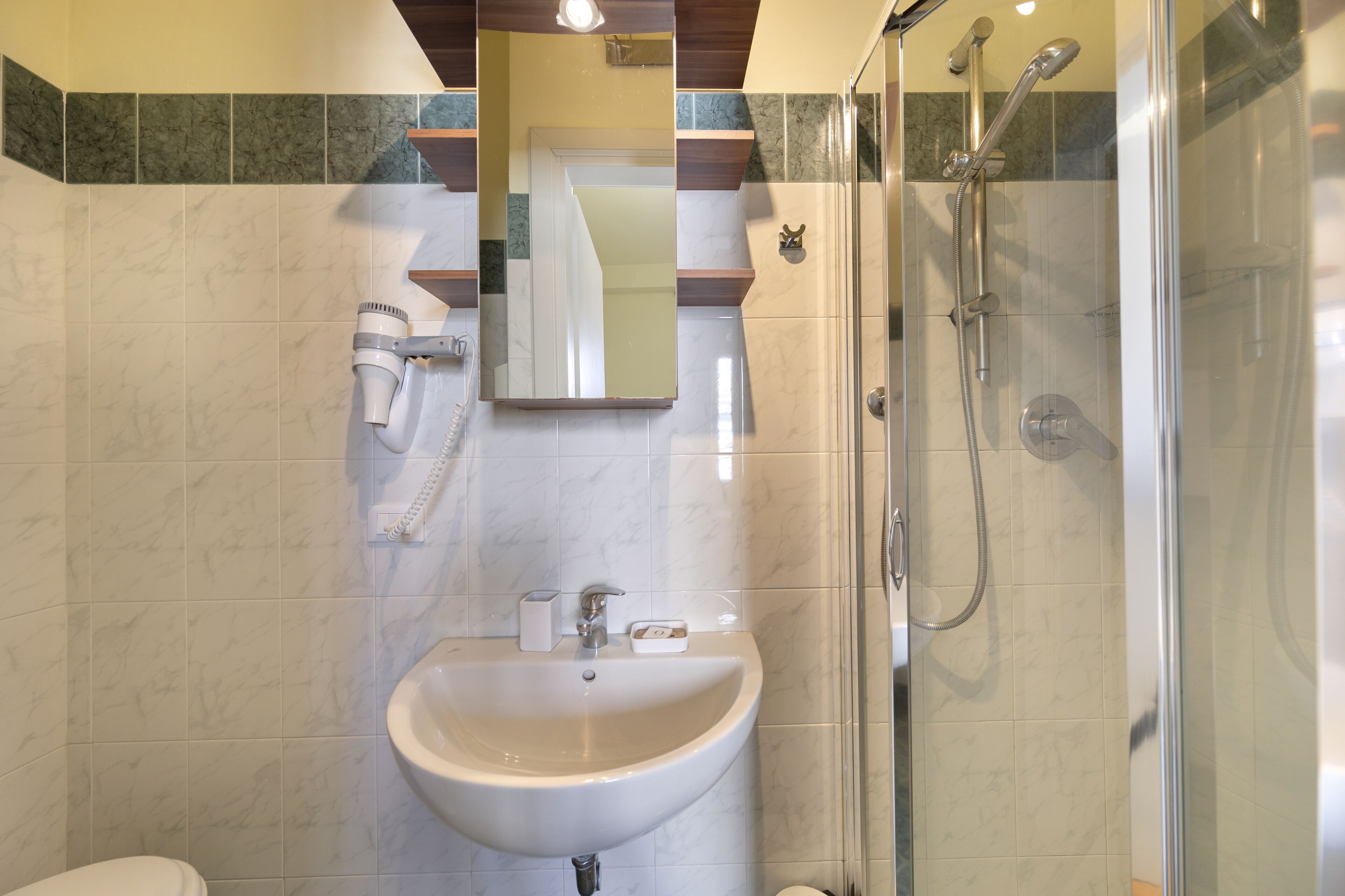 A bathroom with a sink, mirror, and shower.