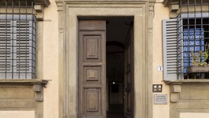 A building entrance with a large wooden door, a sign above the door, and a window with shutters. - Soggiorno Battistero (Florence)
