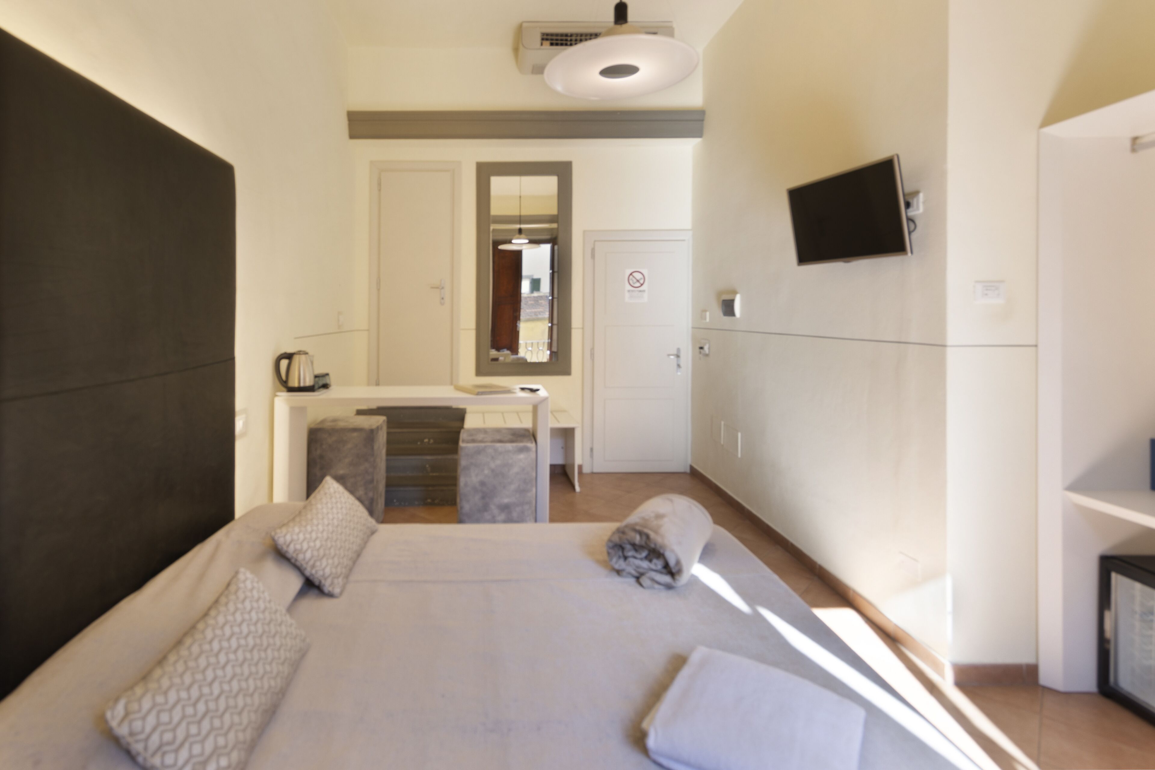 A hotel room with a large bed, a desk with a chair, a television mounted on the wall, and a bathroom visible through an open door.