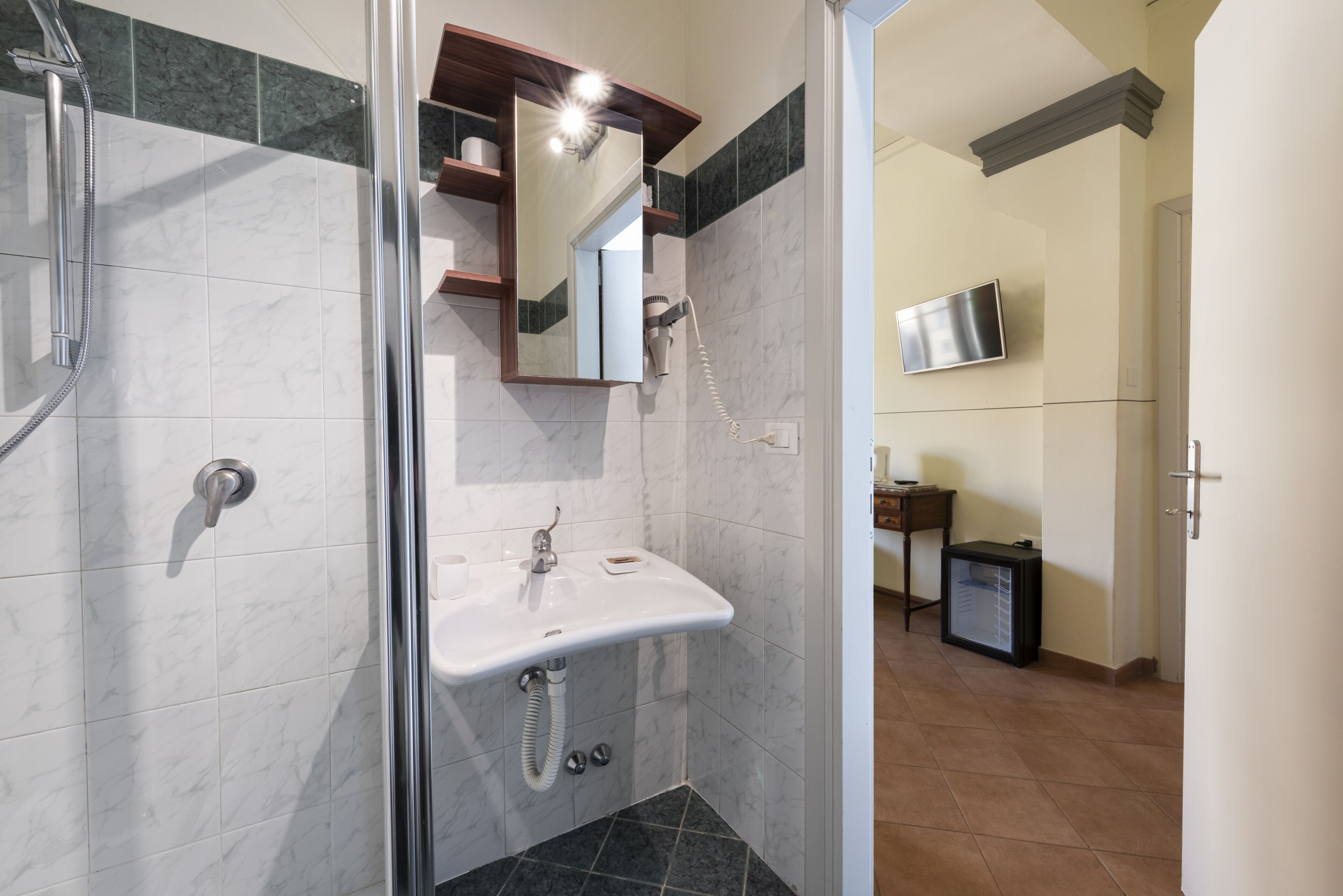 Une salle de bain moderne avec une douche à parois de verre, un lavabo blanc et un miroir au-dessus.