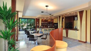Un hall d’hôtel moderne avec un comptoir d’accueil en bois aux lignes courbes, un espace bar et plusieurs coins salon.