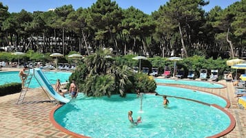 Relax by the pool surrounded by tall pine trees and lounge chairs.