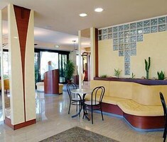 Un'hall dell'albergo con una reception, un'area salotto e un'ampia finestra.