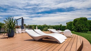 A wooden deck with modern lounge chairs and a potted plant. - Hotel Baya Strand (Cervia)