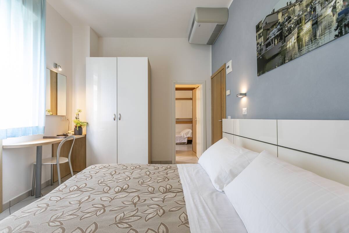 A bedroom with a bed, a desk, and a wardrobe.