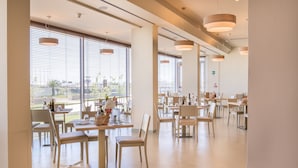 A spacious dining area with large windows, modern pendant lighting, and a clean, minimalist design. - Hotel Baya Strand (Cervia)
