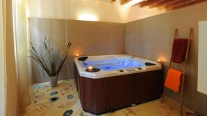 Een badkamer met een bubbelbad, een potplant en een handdoekhouder.