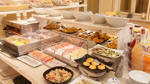 Een buffet met diverse gerechten, waaronder fruit, gebak en drankjes.