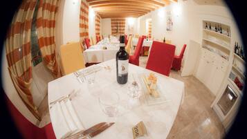 A dining area with tables set for two, a wine bottle, and a number 206 sign on the table.