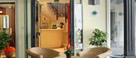 Una habitación con muebles de mimbre, suelo de baldosas y vistas al exterior.