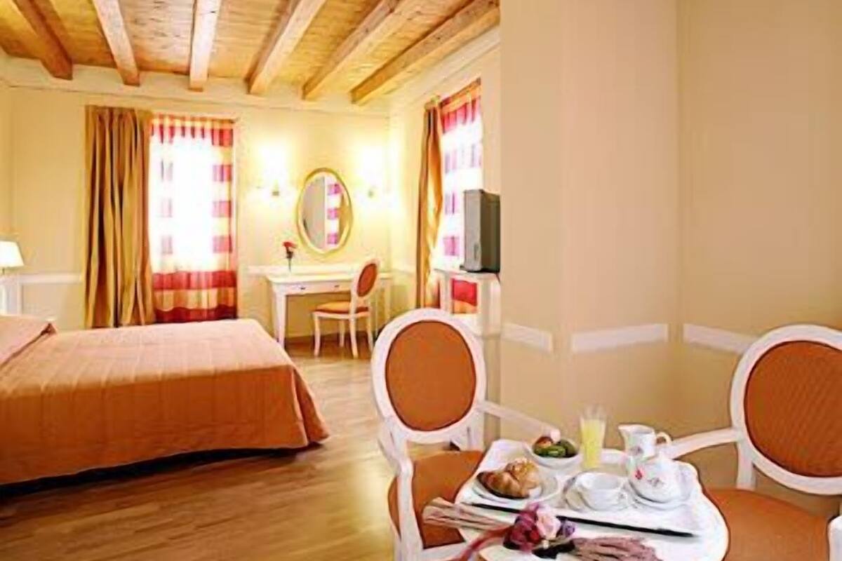Une chambre d’hôtel avec deux lits, un bureau, une chaise et une table à manger avec des articles pour le petit-déjeuner.