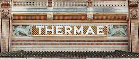 A building facade with the word "THERMAE" prominently displayed, surrounded by intricate tile work and decorative elements.