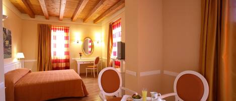 Una habitación de hotel con dos camas, una mesa de comedor con desayuno, un televisor y un escritorio.