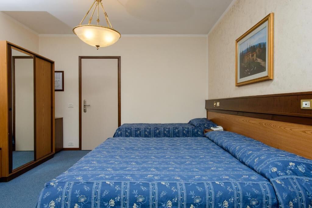 A bedroom with a bed, a wooden headboard, a framed picture on the wall, and a door.