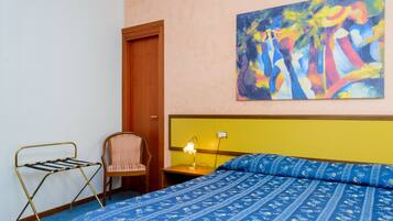 Une chambre à coucher avec un lit, une chaise, une table de chevet, une lampe et un tableau au mur.