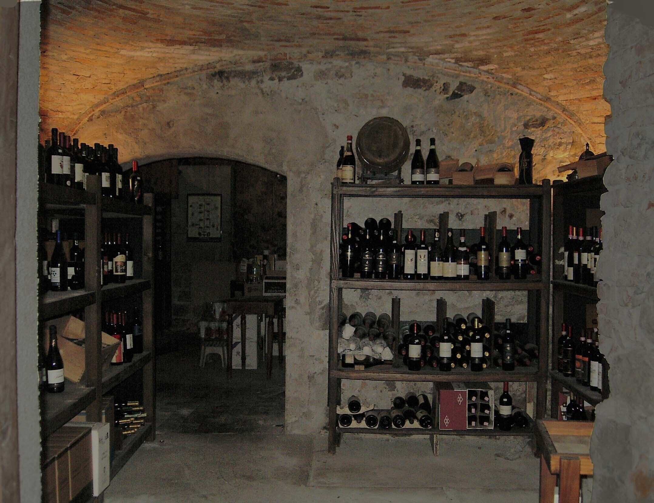 Une cave à vin avec des étagères remplies de bouteilles et un plafond en briques rustiques.