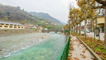 A river with a bridge, buildings, and trees along a walkway.