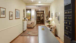 A hallway with framed pictures on the walls, a long table with a lamp, and a cabinet with trophies. - Bes Hotel Papa San Pellegrino Terme (San Pellegrino Terme)