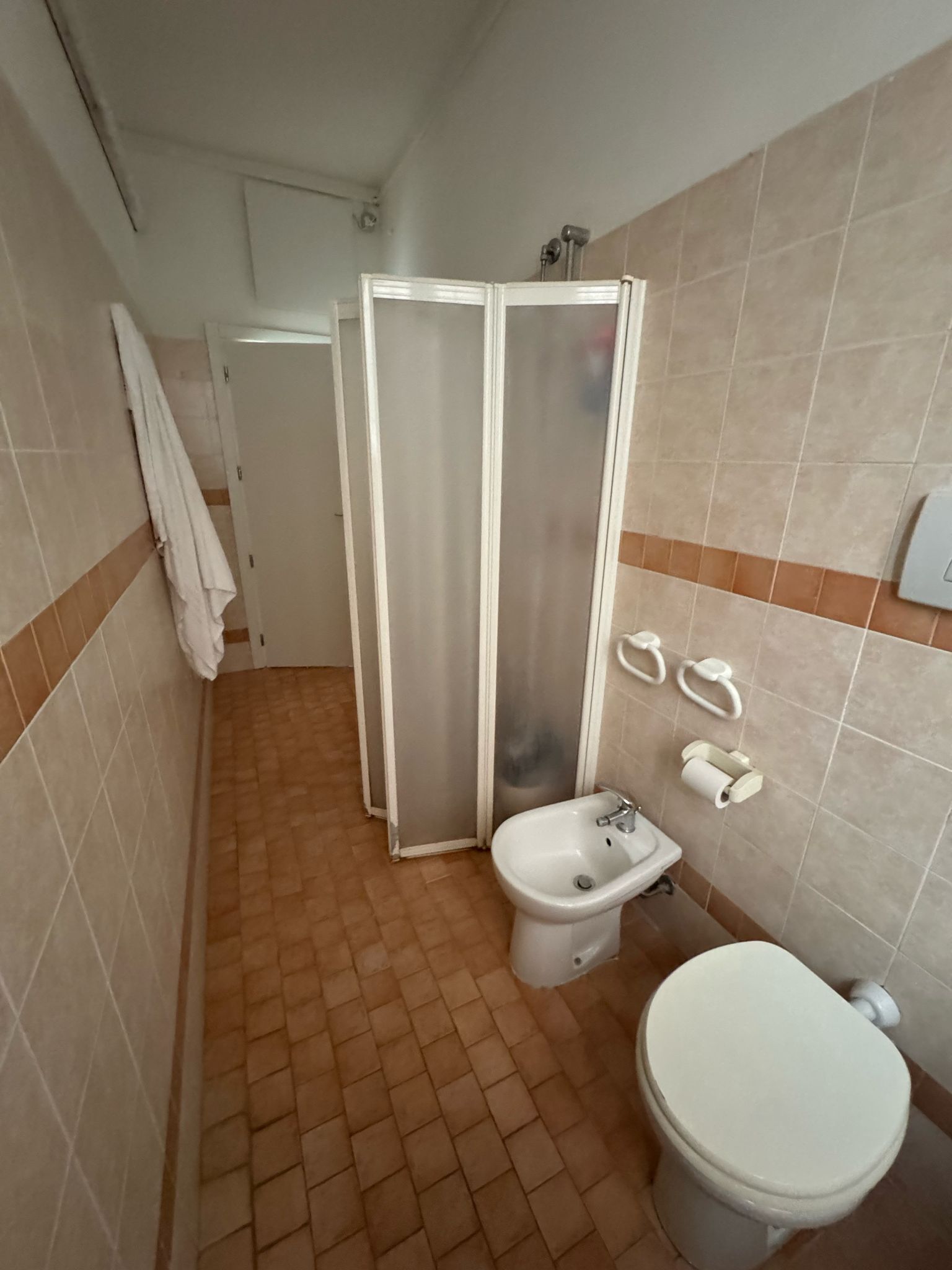 Een badkamer met een hygiëneschuiver, toilet en douchecabine.