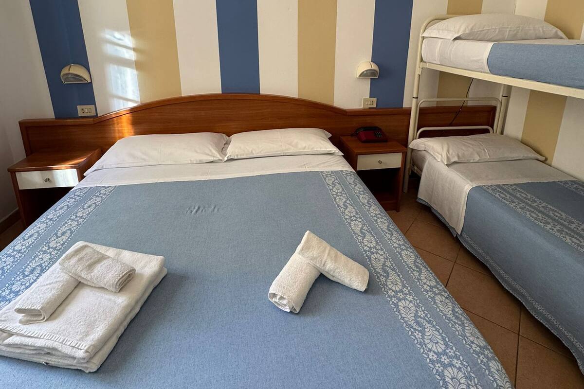 Hotellihuoneessa on kaksi sänkyä, joista toisessa on puinen pääty ja toisessa kerrossänky. Huoneessa on myös kaksi yöpöytää, joista toisessa on lamppu ja toisessa puhelin.