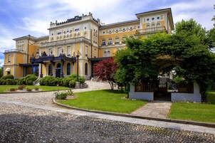 Un edificio grande e histórico con varios balcones y un jardín bien cuidado.
