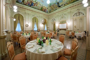 A banquet hall with round tables set for dining, ornate ceiling frescoes, and classical architectural details. - Hotel Villa Malpensa (Vizzola Ticino)
