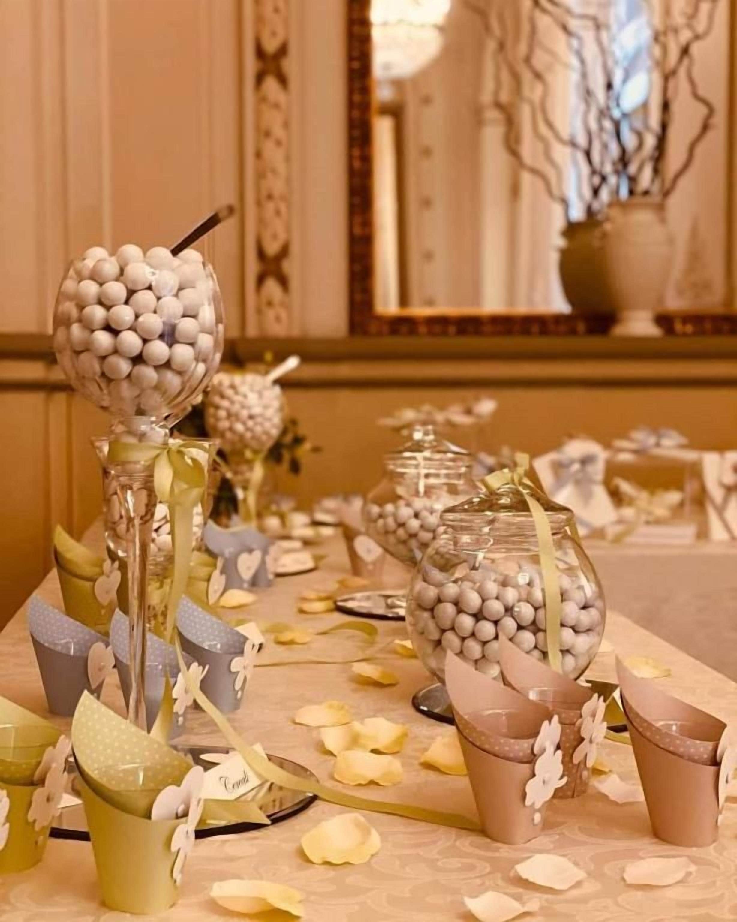Une table ornée de divers objets décoratifs, notamment des bocaux en verre contenant des sphères blanches et des gobelets en papier décorés de rubans.