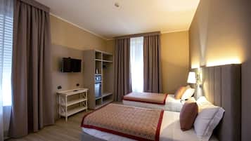 A hotel room with two beds, a TV, a desk, and a wardrobe.