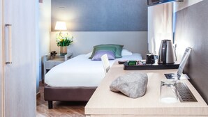 A hotel room with a bed, a desk with a laptop, a coffee maker, and a TV mounted on the wall. - Hotel Oro Blu (Milan)