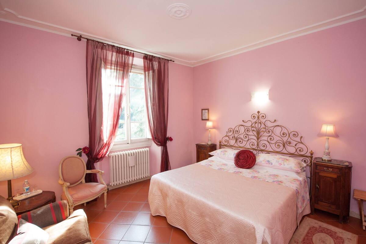 Une chambre à coucher avec un lit, une chaise, une table de chevet et une lampe.