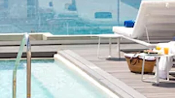 Zona de piscina con vista despejada al océano y al horizonte urbano distante.