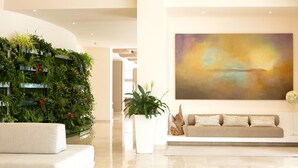 Una sala moderna con un sofá blanco, un cuadro abstracto grande y un jardín vertical.
