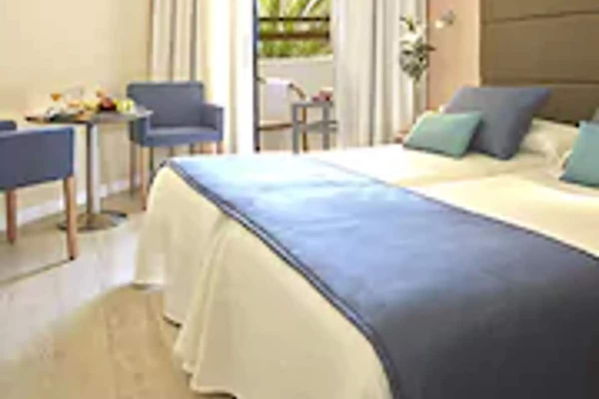 A hotel room with a large bed, a desk, and a chair.