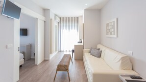 Una sala de estar moderna con un sofá, una mesita y un televisor montado en la pared.