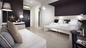 Una habitación de hotel moderna con una cama grande, un sofá, una mesita de noche con lámpara y una decoración con forma de estrella de mar.