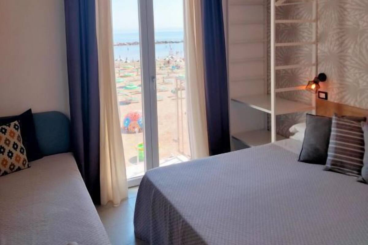 A hotel room with two beds, a view of the beach, and a built-in wardrobe.