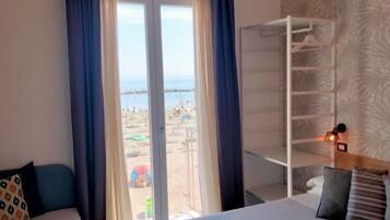 Habitación de hotel con dos camas, vistas a la playa y armario empotrado.