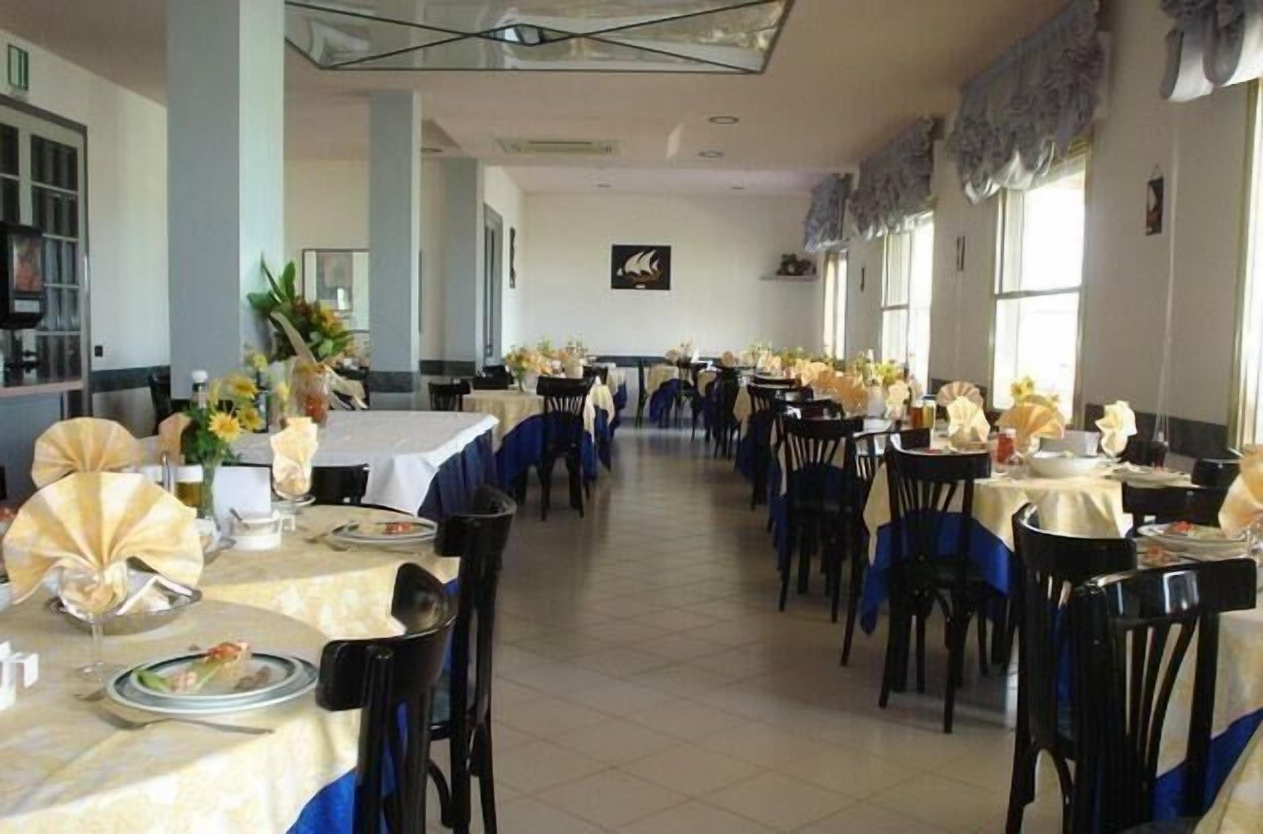 Comedor con varias mesas dispuestas para los huéspedes, con un pasillo central y vistas al interior de la sala.