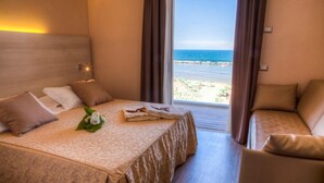 Una habitación de hotel con una cama, un sofá y vista a la playa.