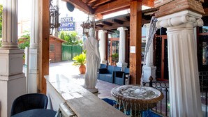 A covered outdoor area with a statue, a fountain, and a sign for a hotel and restaurant.