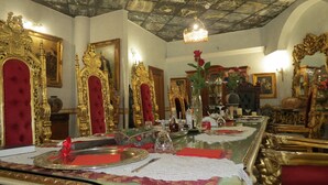 A lavishly decorated room with ornate furniture, a chandelier, and a long dining table set for a meal.