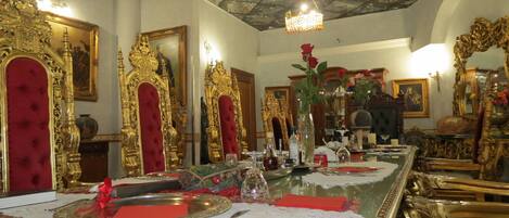 A lavishly decorated room with ornate furniture, a chandelier, and a long dining table set for a meal.